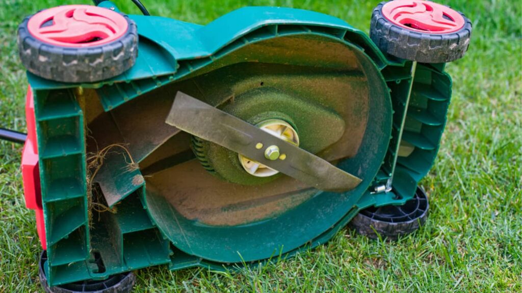 Close-up photo of a lawn mower blade with a green housing in the center. 